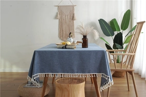 Detail of blue faux linen tablecloth featuring white tassel fringe and premium texture