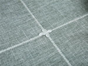Detailed macro view of grey-green linen texture fabric with white floral embroidery
