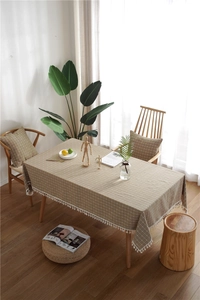 Close-up of brown plaid tablecloth featuring delicate white pom-pom tassel trim details