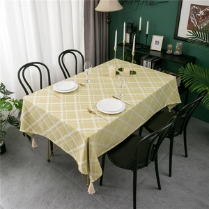 Modern yellow and white checkered tablecloth with tassels on a rectangle wooden dining table