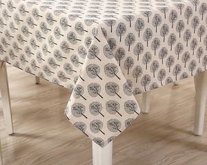 Close-up of beige linen tablecloth with black tree patterns showing the edge drape detail