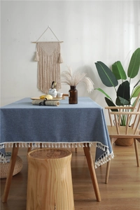 Detail of blue faux linen tablecloth featuring elegant white tassel fringes and fabric texture