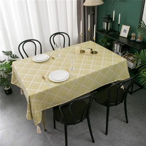 Detail of yellow rectangular tablecloth with white diamond pattern and elegant edge tassels