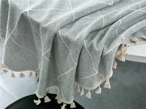 Close-up of sage green checkered tablecloth showing thick fabric texture and cream fringe