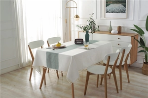 Detail of waterproof dining table runner with Morandi green patterns and white tassels