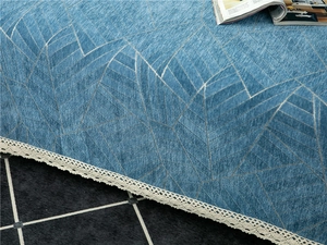 Detail of blue chenille sofa cover featuring geometric leaf texture and cream lace trim
