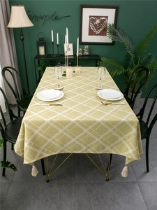 Detail of yellow-green checkered tablecloth with thick texture and cream corner tassels