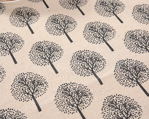 Close-up of linen fabric texture with creative black tree patterns on a beige tablecloth