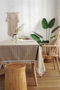 Detail of coffee brown checkered tablecloth with white tassels and faux linen texture
