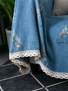 Detailed view of blue chenille sofa cover with white lace trim and feather jacquard pattern