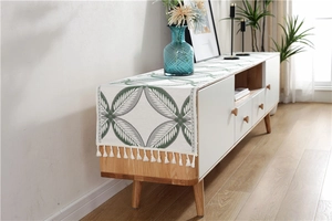 Detailed close-up of chenille table runner featuring green leaf patterns and cotton tassels