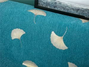 Macro detail of thick teal chenille fabric with silver ginkgo leaf jacquard embroidery