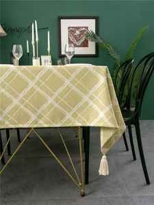 Detail showing light green linen tablecloth with white check pattern and cotton tassels