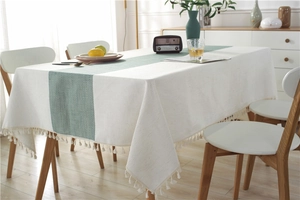 Close-up of waterproof linen table runner with green herringbone pattern and white tassels