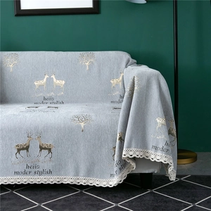 Detail of chenille sofa cover with deer pattern, lace edges and stylish text decoration
