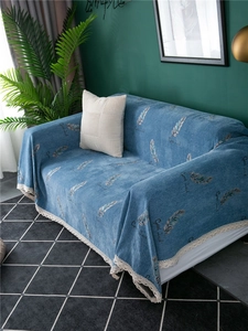 Detail of blue chenille sofa cover with feather pattern, Good Luck print, and lace trim