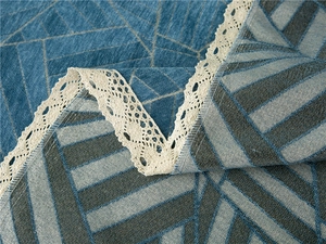 Detail of chenille sofa cover with geometric pattern and white crochet lace trim edge