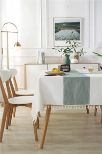 Close-up of modern sage green herringbone table runner with elegant white tassels
