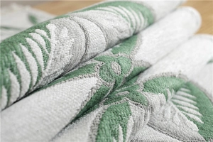 Macro detail of chenille table runner featuring green leaf jacquard and thick texture