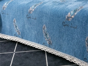 Detail of blue chenille sofa cover featuring feather prints and delicate lace edges
