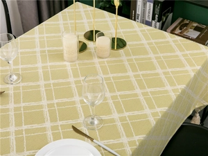 Detailed close-up of yellow checkered tablecloth with elegant off-white tassel trim accents