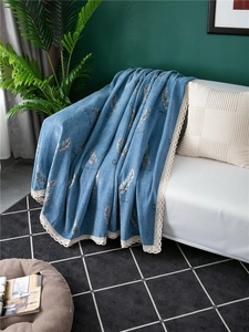 Detail of blue chenille sofa cover with feather pattern and white lace edge finish
