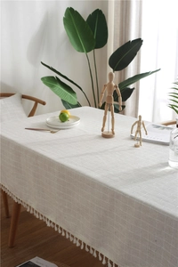 Detail of light beige table cloth with fine white grid pattern and elegant fringe edges