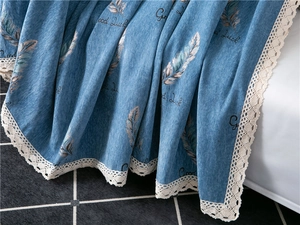 Detail of blue chenille sofa cover with feather patterns and white lace border edge
