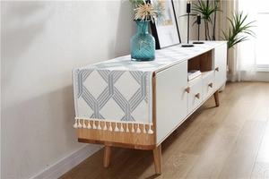 Detail of blue geometric chenille table runner with white fringe on a wooden cabinet