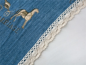 Close-up of thick chenille fabric featuring classic carriage print and delicate lace trim