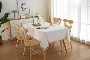 Detail shot of a white rectangle tablecloth featuring decorative fringe tassels on the edges