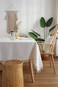 Detail shot of cream plaid tablecloth with decorative white tassel trim and woven texture