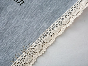 Detailed close-up of grey chenille fabric with letter embroidery and lace trim decoration