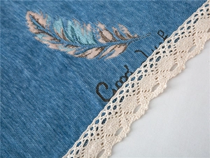 Detail of blue chenille sofa cover with feather print and delicate white lace edge