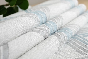 Close-up of chenille table runner featuring blue and grey woven patterns with fringe