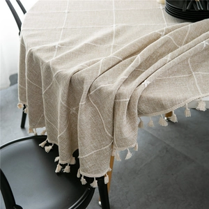 Detail of beige jacquard checkered tablecloth featuring rustic texture and fringe edges