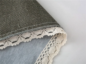Close-up of chenille sofa cover with intricate white crochet lace edge and textured fabric