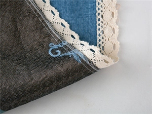 Detail of chenille sofa cover showing blue denim fabric with white lace embroidery edges