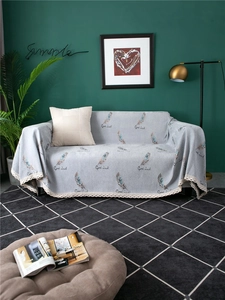 Detail of gray chenille sofa cover with feather patterns, Good Luck text and lace edges
