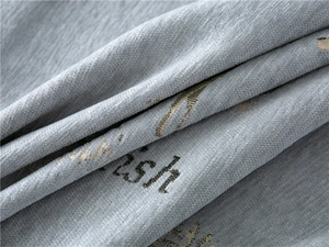 Detail of grey chenille fabric with gold embroidered deer and wish text pattern