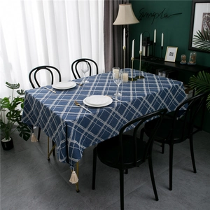 Blue plaid rectangular tablecloth with tassel trim in a modern minimalist dining setting