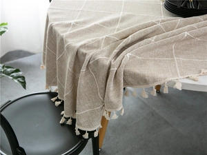 Detail of light coffee plaid tablecloth featuring white checkered patterns and tassel fringe