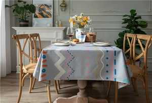 Detail view of modern geometric printed tablecloth on a wooden dining table in a cozy room