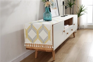Close-up of chenille table runner with yellow geometric pattern and white tassels detail