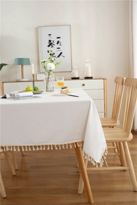 Macro detail of thick white cotton linen tablecloth with cream cotton fringe tassels