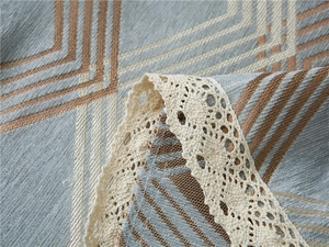 Close-up of gray geometric chenille fabric with delicate off-white crochet lace border