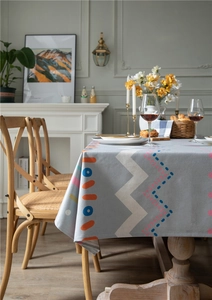 Detail of modern tablecloth with geometric orange and blue patterns on grey fabric