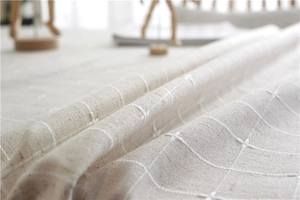 Macro shot of beige plaid jacquard fabric texture and soft drape of rectangular tablecloth