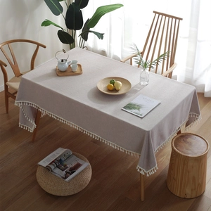 Modern light grey linen tablecloth with white tassel fringe in a Nordic dining setting