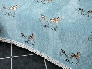 Detailed view of blue chenille sofa cover with carriage pattern and white lace edge